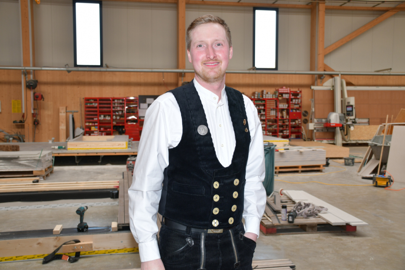 Der stellvertretende Innungsobermeister Benedikt Lachner in der traditionellen Zimmerer-Kluft in der Produktionshalle seines Betriebs. Foto: Riffert/JOB 2026